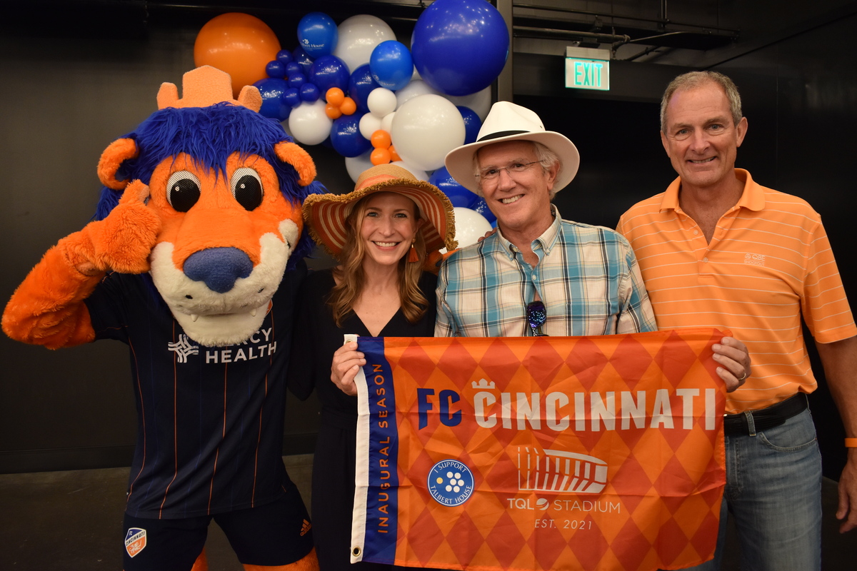 Three people FC Cincinnati mascot and sign